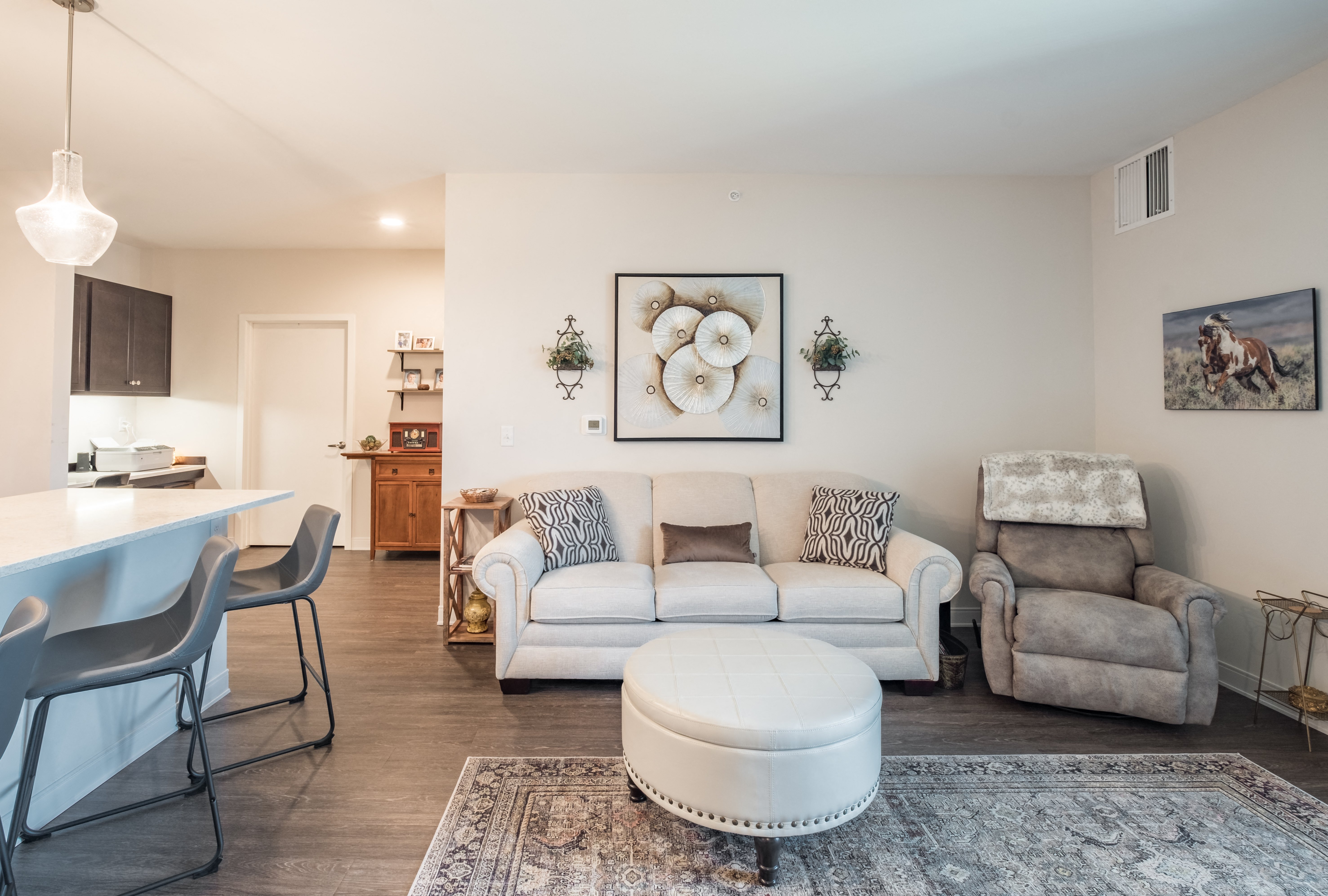 A living room with a white couch, a grey armchair, and a white ottoman.